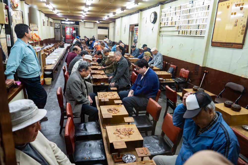 Japanese people playing Shogi or Japanese chess at Kuromon Ichiba Market in Osaka.