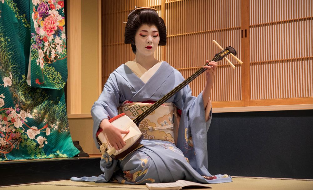 A geisha plays the shamisen, which produces a sound that is distinctively Japanese.